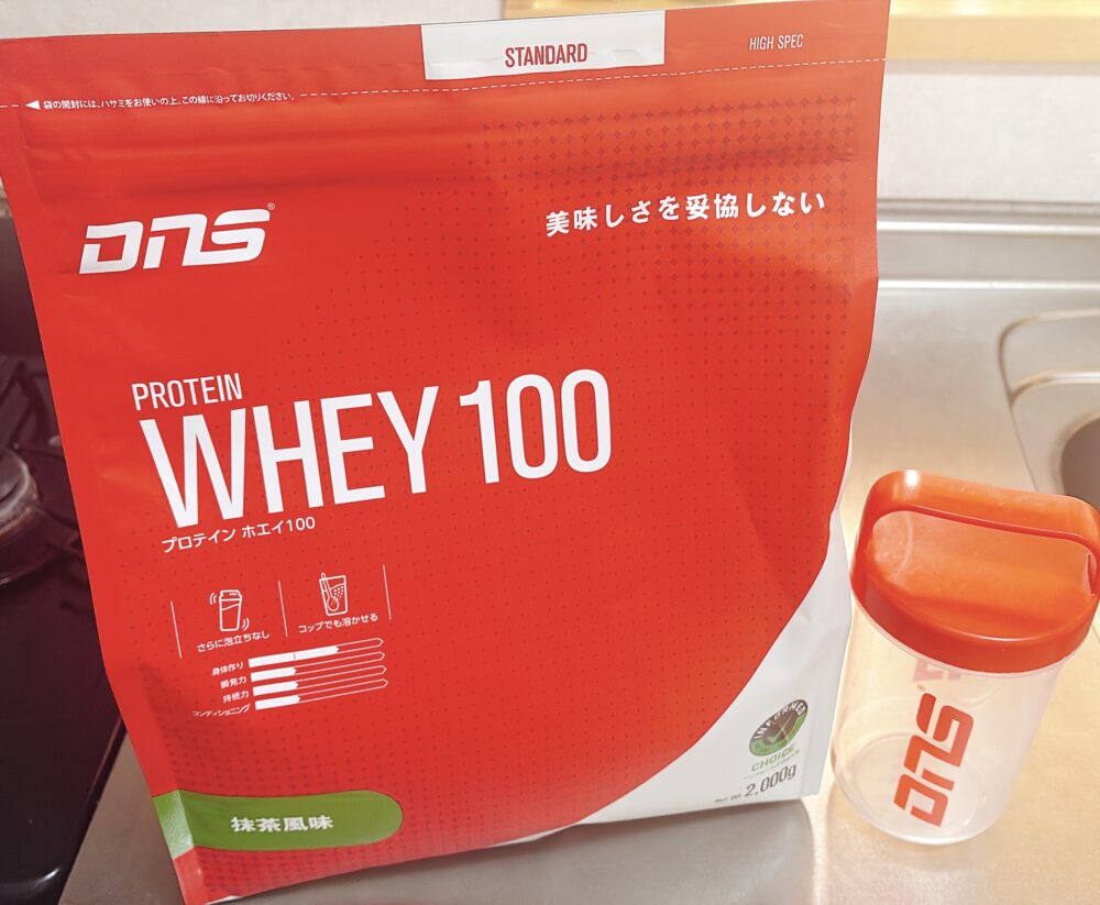 DNSプロテイン WHEY100 抹茶風味と専用シェイカー。たんぱく質補給に便利なホエイプロテインで、溶けやすく美味しさにこだわった商品。